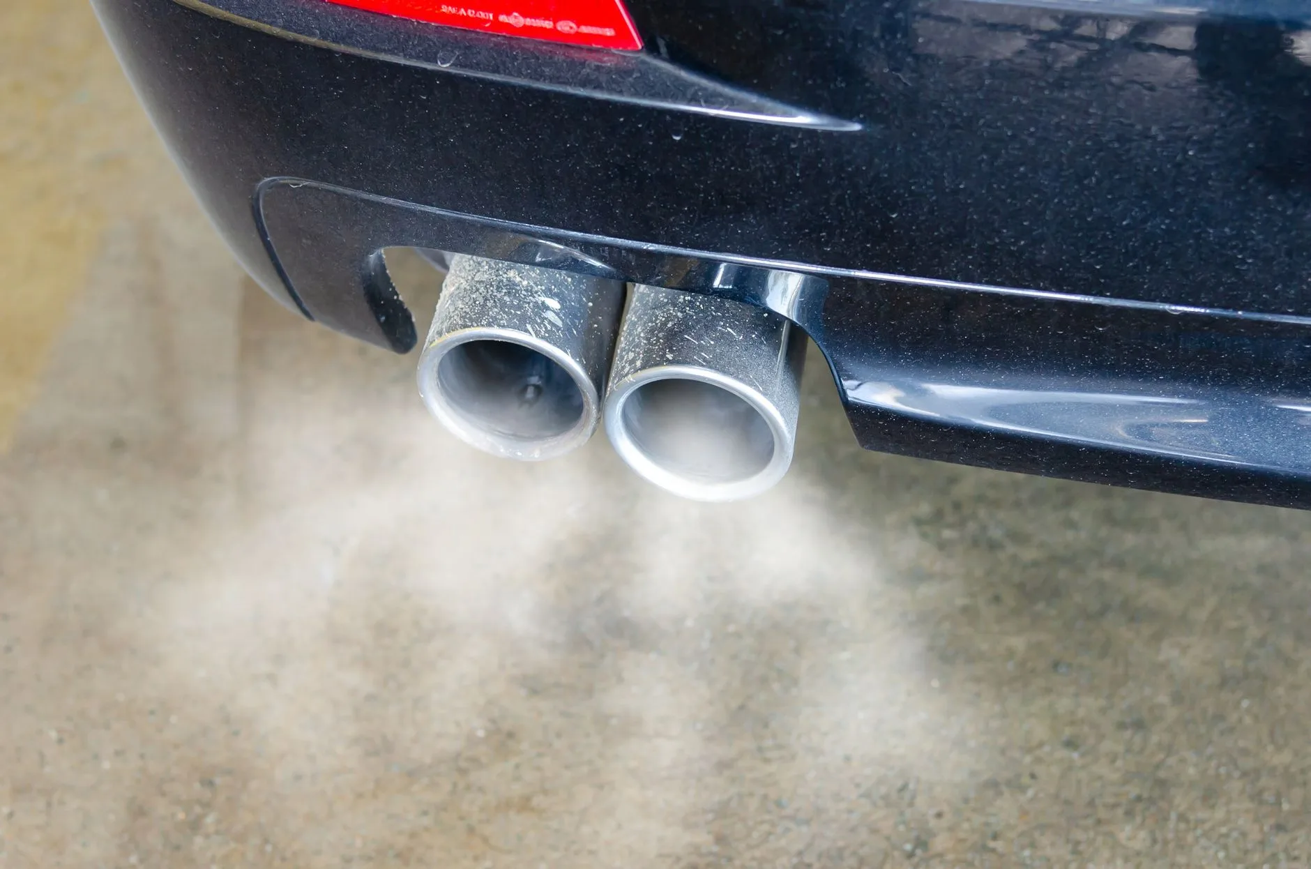 Fumée blanche à l'échappement s'échappant du pot d'une voiture moteur en marche